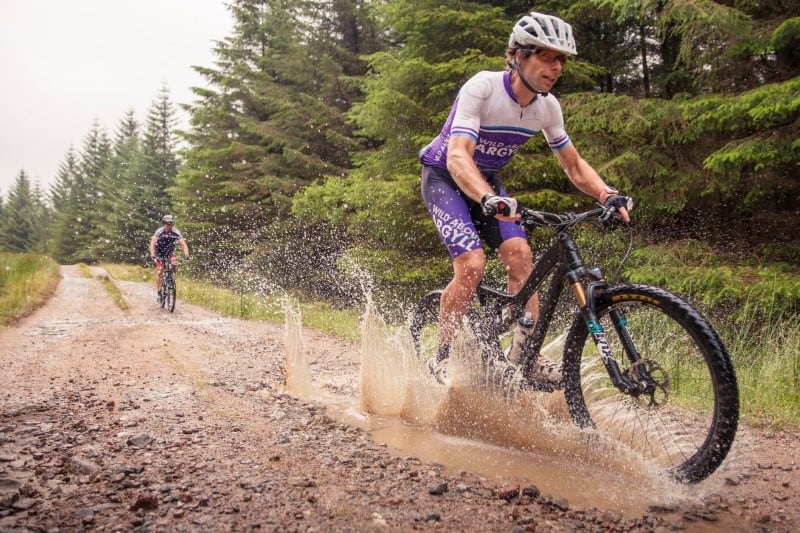 Two men are riding adventure road bikes through the puddles